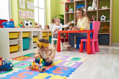 Anaokulunda kızlarla oynayan öğretmen.