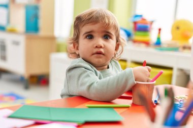 Tapılası İspanyol çocuk. Anaokulunun önünde kağıda resim çiziyor.