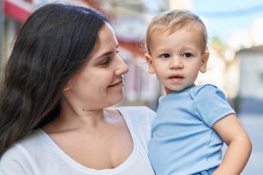 Anne ve oğlu sokakta kendinden emin gülümsüyor.