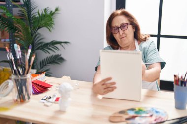 Senior woman artist drawing on notebook at art studio
