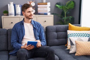 Evdeki koltukta oturan beyaz bir adam dokunmatik ped kullanıyor.