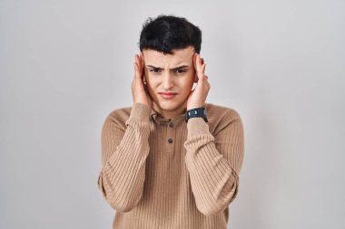 Non binary person standing over isolated background with hand on head, headache because stress. suffering migraine. 