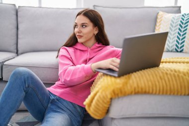 Young woman using laptop sitting on floor at home