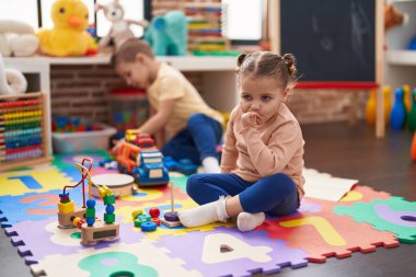 Two kids playing with cars toy sitting on floor at kindergarten
