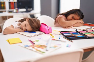 Two kids students sitting on table sleeping at classroom