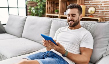 Evde dokunmatik ped kullanan, kendine güvenen genç bir İspanyol.