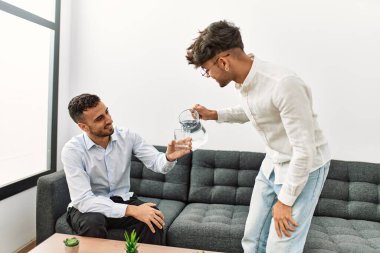 İki İspanyol iş adamı gülerek ofise su dökerler.