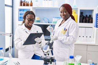 Afrika kökenli Amerikalı kadın bilim adamı laboratuardaki belgelerde test tüpü tutuyor.