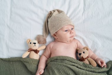 Adorable caucasian baby lying on bed with relaxed expression at bedroom
