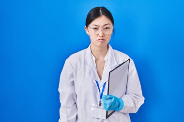 Chinese young woman working at scientist laboratory depressed and worry for distress, crying angry and afraid. sad expression. 