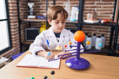 Tapılası İspanyol astronom öğrenci laboratuvar sınıfında not defterine yazarak gezegensel işler yapıyor.