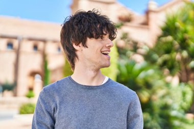 Parkta kendinden emin gülümseyen İspanyol genç adam.