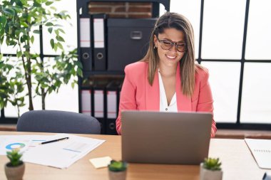 Ofiste çalışan genç İspanyol iş kadını laptopu kullanıyor.