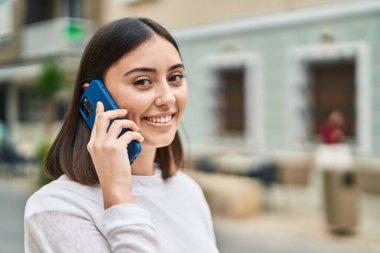 Genç İspanyol kadın gülümsüyor. Kendine güveniyor. Akıllı telefondan konuşuyor.