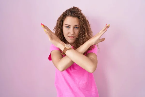 年轻的高加索女人站在粉红的背景音乐旁边 交叉着双臂做着消极的手势 生气的脸 — 图库照片