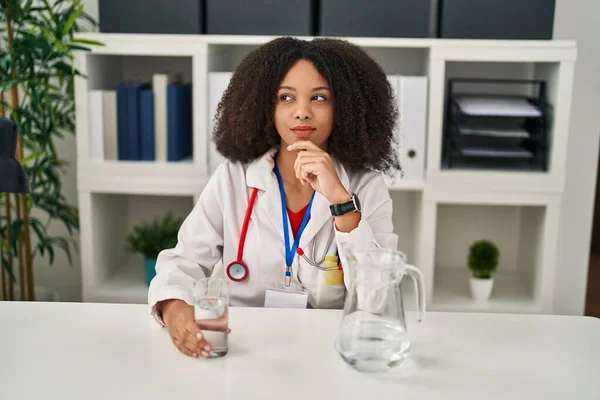 Young African American Doctor Woman Drinking Water Clinic Serious Face — Stock fotografie