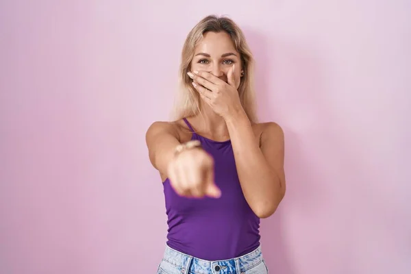 Jonge Blonde Vrouw Staan Roze Achtergrond Lachen Naar Wijzend Vinger — Stockfoto