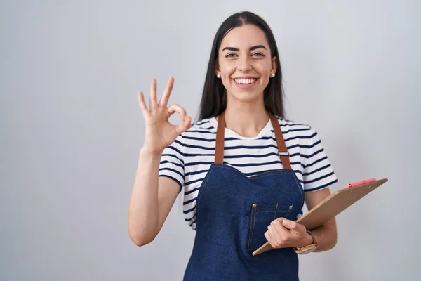 Young Brunette Woman Wearing Professional Waitress Apron Clipboard Doing Sign — Zdjęcie stockowe