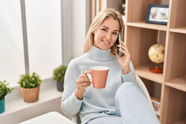 Young Blonde Woman Talking Smartphone Drinking Coffee Home — Stockfoto