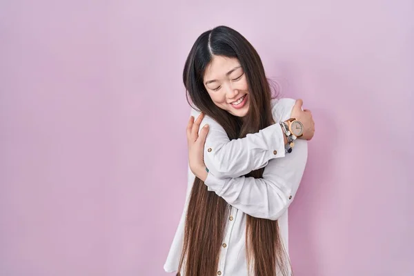 Chinese Young Woman Standing Pink Background Hugging Oneself Happy Positive — Photo