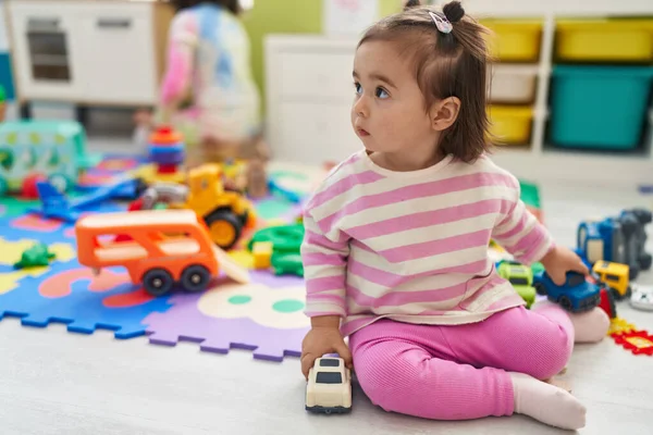 愛らしい中国の幼児遊びます車のおもちゃで床に座って幼稚園 — ストック写真