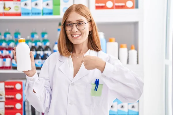 在药店工作的红头发年轻女人拿着防晒霜指着一个笑得很开心很自豪的人 — 图库照片