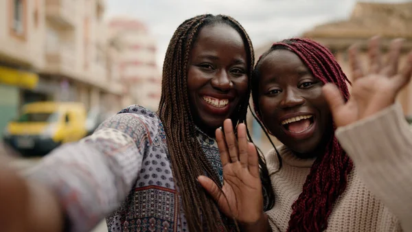 Two african american friends smiling confident having video call at street