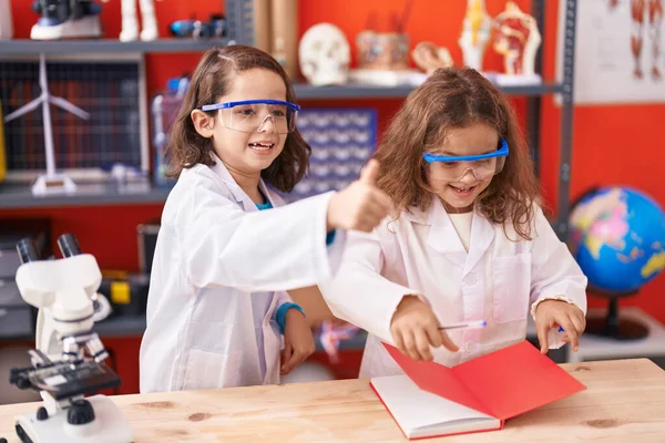 两个在笔记本上写字的孩子在实验室里用大拇指做着一个不错的手势 — 图库照片