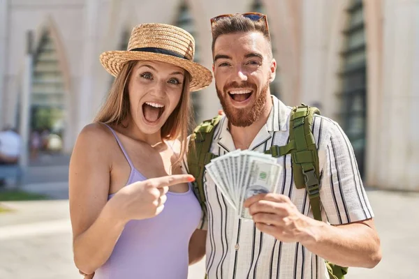 Young Tourist Couple Holding Dollars Banknotes Smiling Happy Pointing Hand — Stock Photo, Image