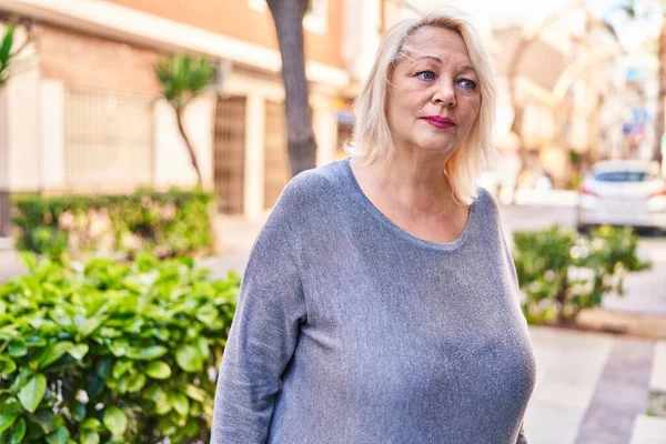 Sokakta duran orta yaşlı sarışın kadın.