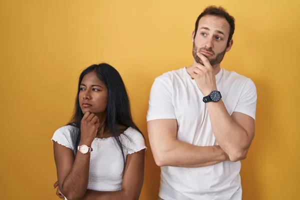Interracial Couple Standing Yellow Background Thinking Worried Question Concerned Nervous — ストック写真