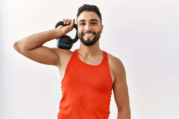 Hombre Árabe Joven Sonriendo Entrenamiento Seguro Con Kettlebell Centro Deportivo —  Fotos de Stock