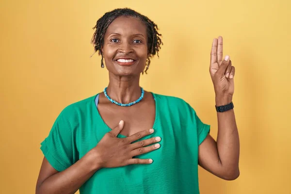 African Woman Dreadlocks Standing Yellow Background Smiling Swearing Hand Chest — Stockfoto