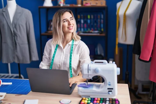 服装厂的年轻女性裁缝笑着自信地使用笔记本电脑 — 图库照片