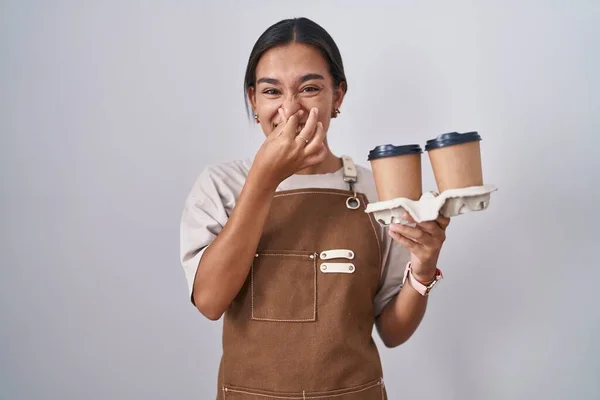 Young Hispanic Woman Wearing Professional Waitress Apron Holding Coffee Smelling — Zdjęcie stockowe