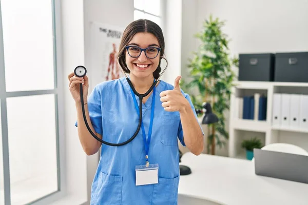 Młoda Latynoska Lekarka Nosząca Stetoskop Klinice Uśmiechnięta Szczęśliwa Pozytywna Kciukiem — Zdjęcie stockowe