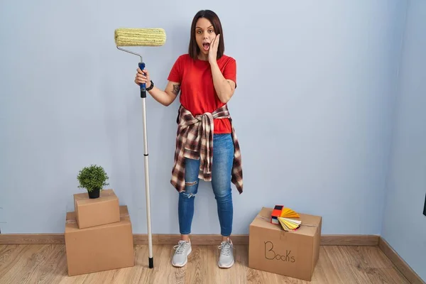 Young Hispanic Woman Painting Home Walls Paint Roller Afraid Shocked — Stockfoto