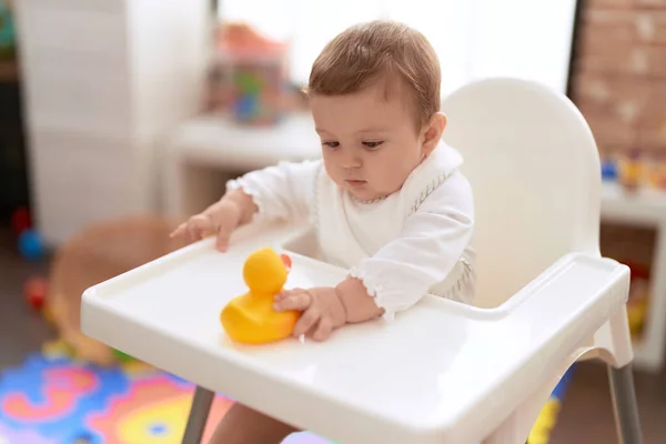 幼稚园可敬的幼儿坐在婴儿高椅子上 抱着橡胶鸭玩具 — 图库照片