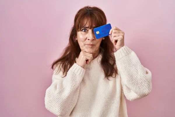 Hiszpanka Średnim Wieku Trzymająca Kartę Kredytową Zakrywającą Oko Poważną Miną — Zdjęcie stockowe