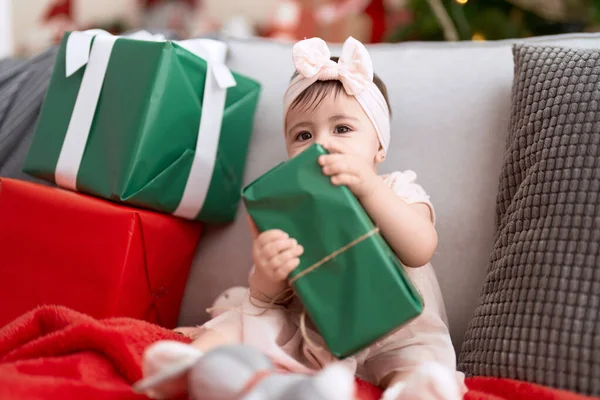 스러운 아기가 크리스마스 선물을 소파에 앉아서 — 스톡 사진