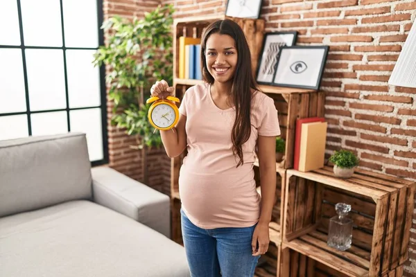 Young Pregnant Woman Holding Alarm Clock Due Date Looking Positive — Stockfoto