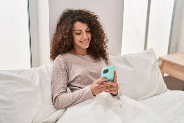 Young Hispanic Woman Using Smartphone Sitting Bed Bedroom — 图库照片