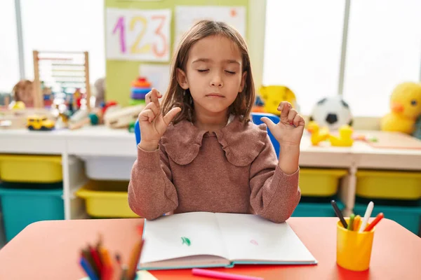 Adorable Hispanic Girl Preschool Student Sitting Table Crossing Fingers Kindergarten — Fotografia de Stock