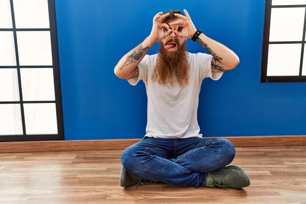 Redhead Man Long Beard Sitting Floor Empty Room Doing Gesture —  Fotos de Stock