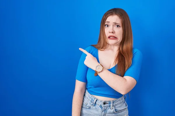Redhead Woman Standing Blue Background Pointing Aside Worried Nervous Forefinger — Stock Photo, Image