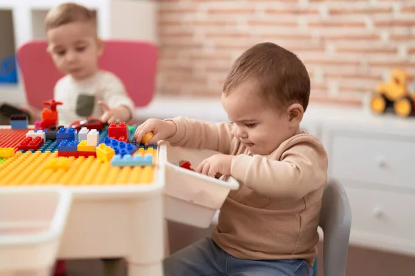 2人の愛らしい幼児が遊んでいます建設ブロックでテーブルの上に座って幼稚園 — ストック写真