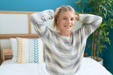 Young blonde woman smiling confident sitting on bed at bedroom