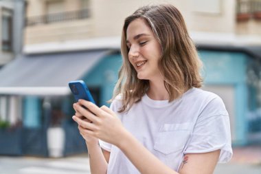 Sokakta akıllı telefon kullanan kendine güvenen genç bir kadın.