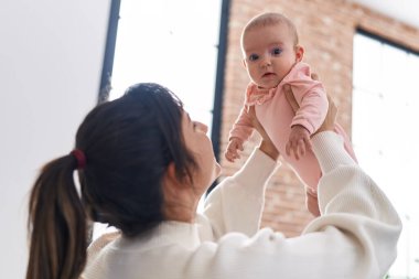 Mother and daughter smiling confident sitting on bed at home