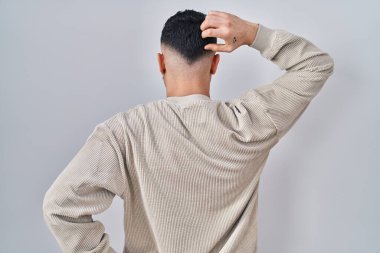 Young handsome man standing over isolated background backwards thinking about doubt with hand on head 